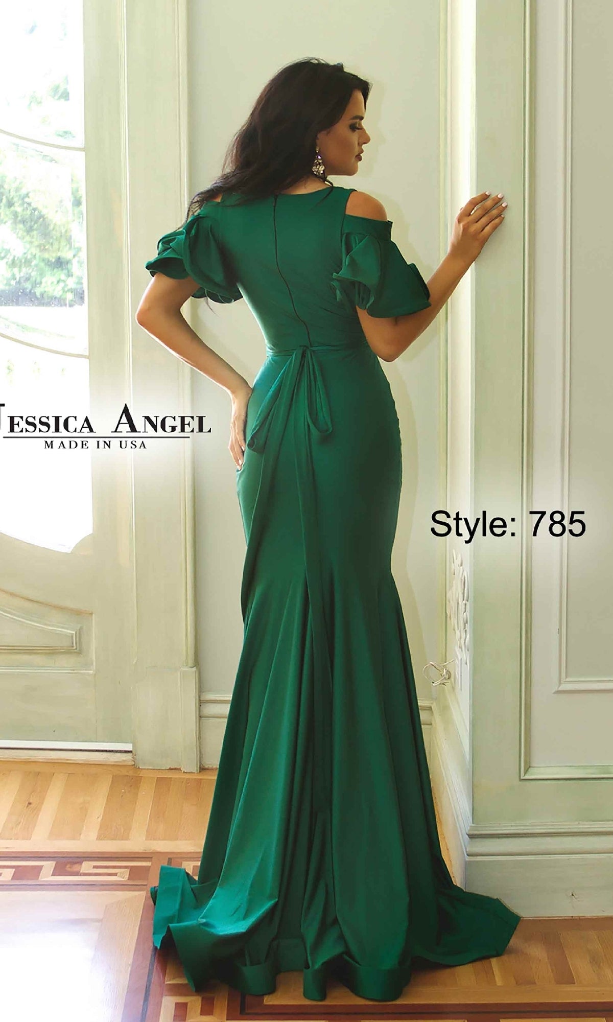 A woman poses in a bright, elegant room wearing the Cold-Shoulder Long Prom Dress: Jessica Angel 785, featuring a fitted green mermaid silhouette with short ruffled sleeves and a bow at the back. Text reads